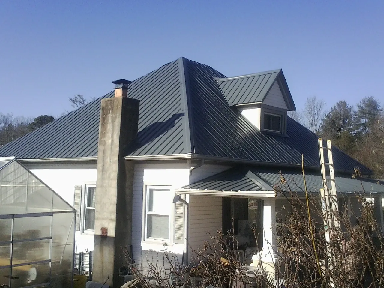 Dark blue standing seam metal roof on a white farmhouse with dormer — Slate & Tile Roof Repair by Roofing Brothers in Lakebay