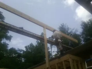 Carpenter setting a ridge beam over a new addition frame — Ice Dam Removal by Roofing Brothers in Lakebay