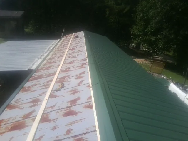 Old rusted panels beside newly installed green metal roofing — Wind Damage Roof Repair by Roofing Brothers in Lakebay
