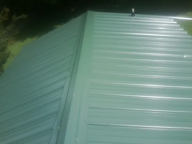 New green metal panels meeting at the ridge of a roof — Flat Roof Repair work by our crew in Lakebay