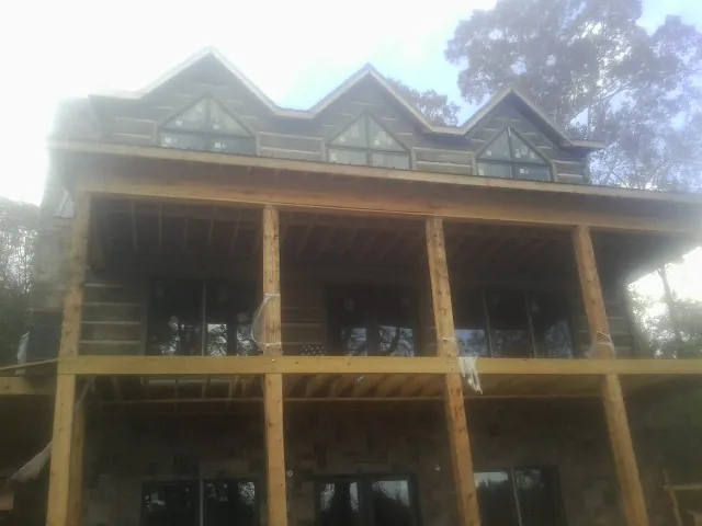 Dormers and porch framing on a large log home under construction — Roof Coating work by our crew in Lakebay