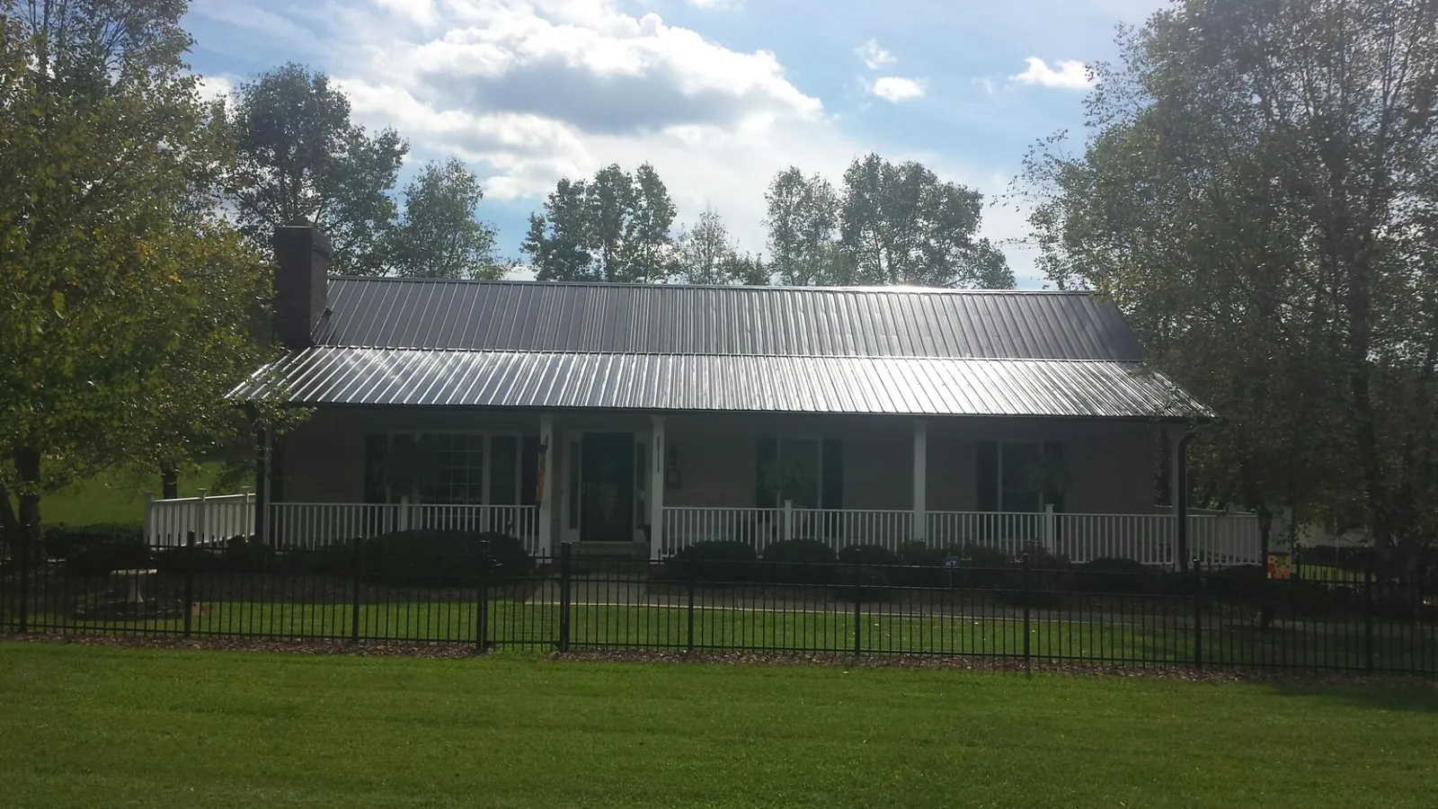 Gray metal roof on a brick ranch with a full width front porch — Gutter Guard Installation work by our crew in Lakebay
