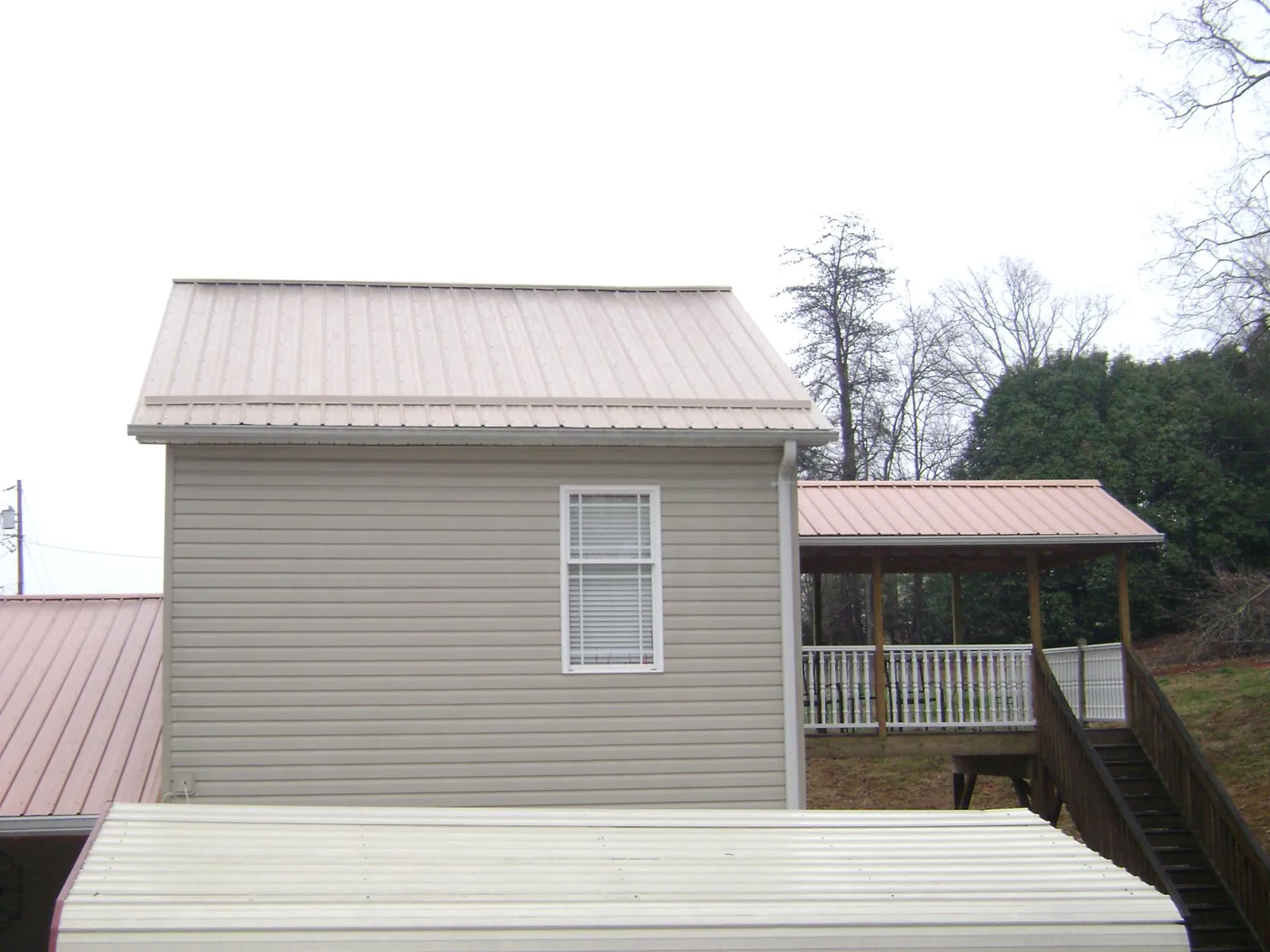 Tan metal roofs on a two story addition and attached porch, from a Roof Replacement job in Lakebay