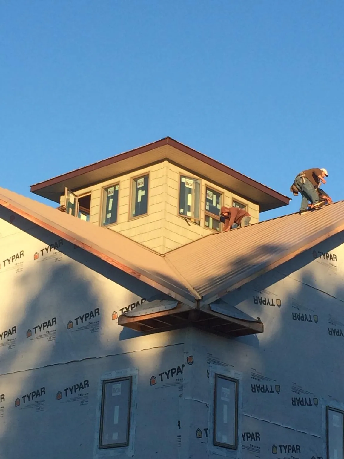 Roofers working around a rooftop cupola on a new metal roof at sunset — Roof Waterproofing in Lakebay by Roofing Brothers